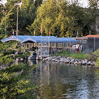  A photo of looking out at Yahara River and and across the river there is a boathouse with a pier with pondtoon boats